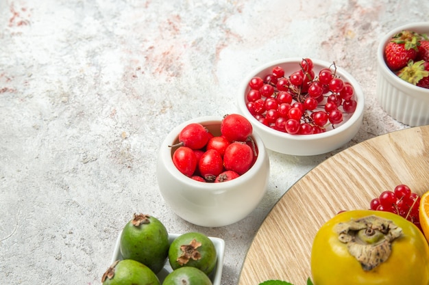 Vista frontale composizione di frutta frutti diversi su tavola bianca frutti di bosco maturi freschi