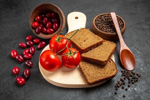 Vista frontale cornioli rossi freschi con pagnotte di pane e pomodori su uno spazio grigio