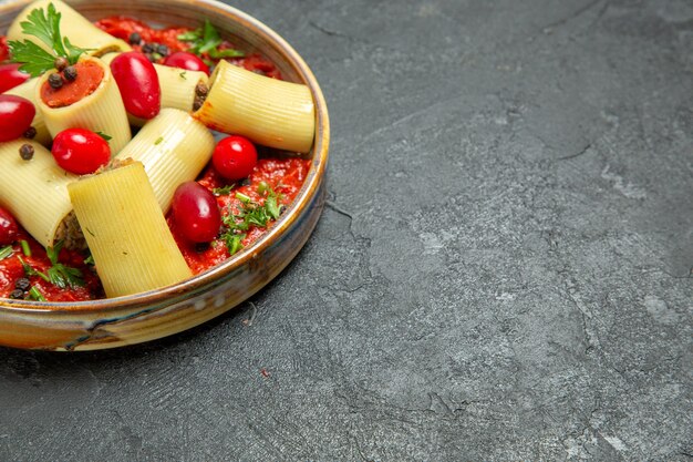 Vista frontale cucinato delizioso pasto italiano di pasta con carne e salsa di pomodoro su cibo di salsa di carne di pasta di pasta del pavimento grigio