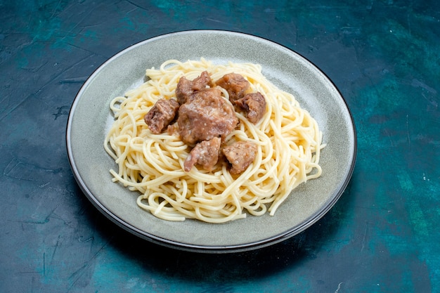 Vista frontale cucinato pasta italiana con carne affettata all'interno della piastra sulla superficie blu pasta italia cibo pasto cena pasta carne