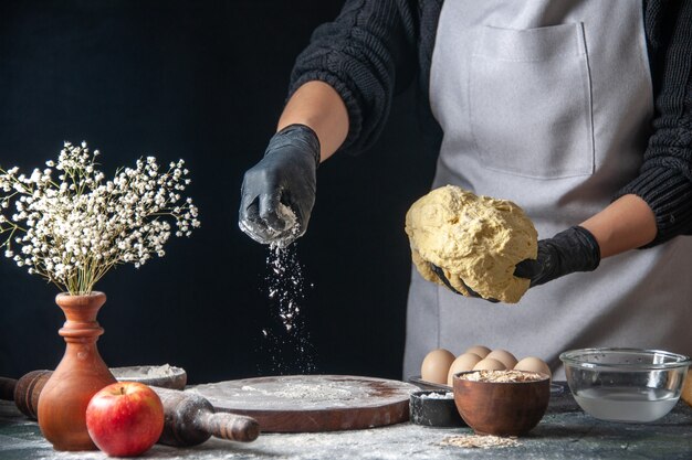 Vista frontale cuoca stendere la pasta sul lavoro scuro torta di pasta forno pasticceria cucina hotcake cucina panetteria uovo