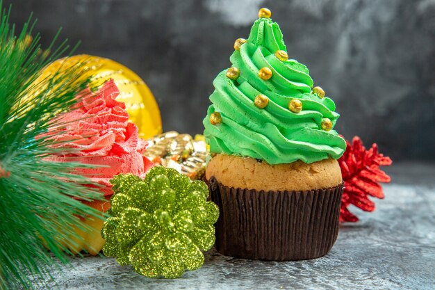 Vista frontale cupcakes colorati giocattoli albero di natale su grigio on
