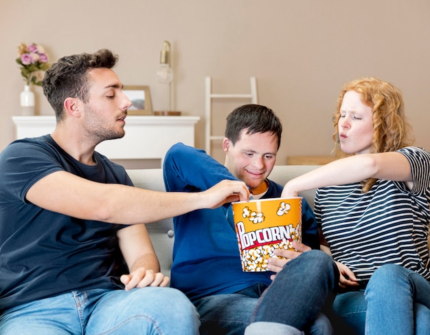 Vista frontale degli amici che mangiano popcorn a casa