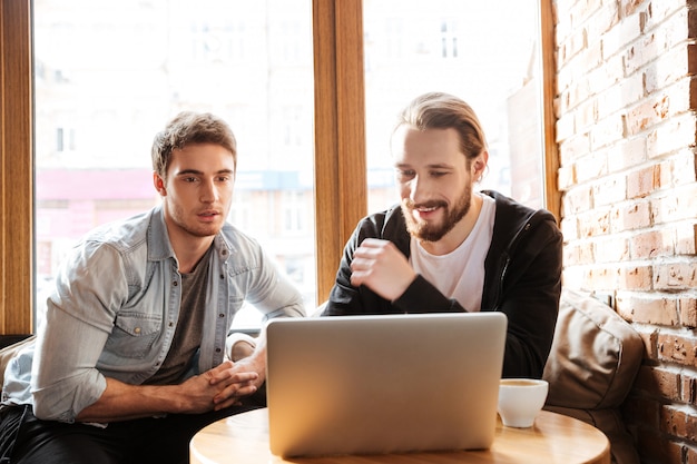 Vista frontale degli amici con il computer portatile in caffè