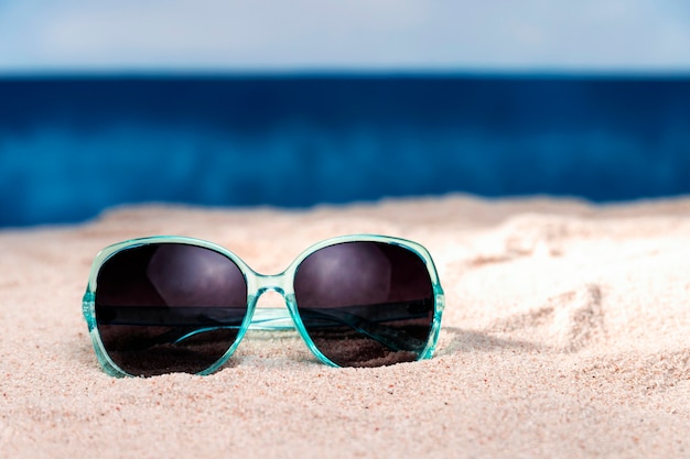 Vista frontale degli occhiali da sole sulla sabbia della spiaggia