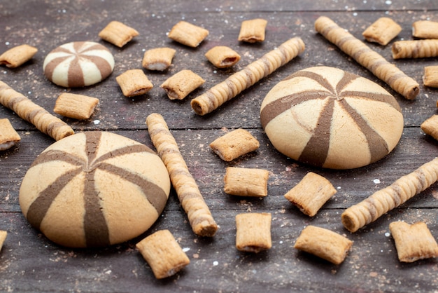 Vista frontale dei biscotti al cioccolato rotondi e formati a lungo sulla superficie scura