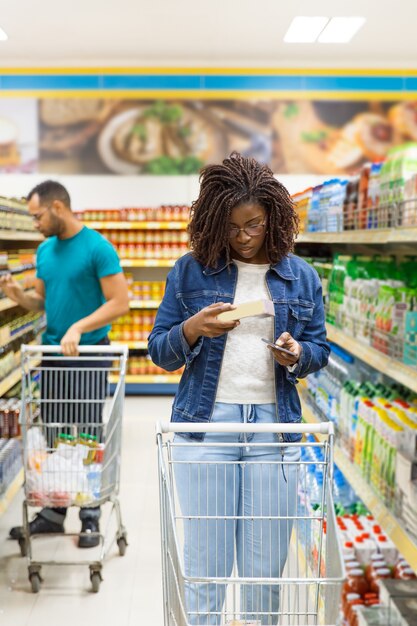 Vista frontale dei clienti che camminano nella navata laterale con i carrelli della spesa