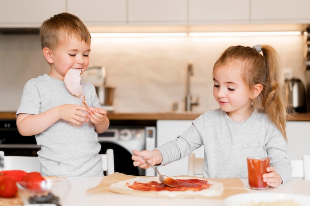 Vista frontale dei fratelli che cucinano a casa