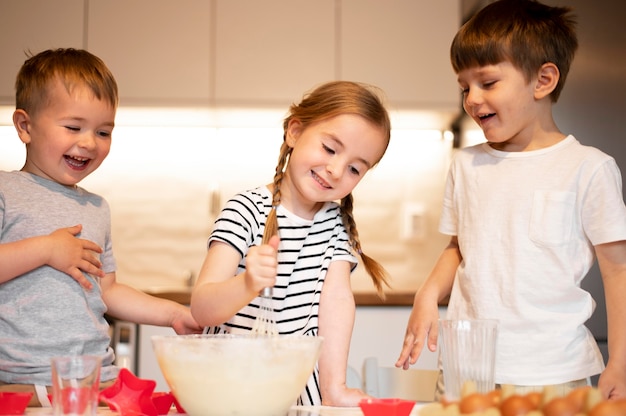 Vista frontale dei fratelli germani svegli che cucinano a casa