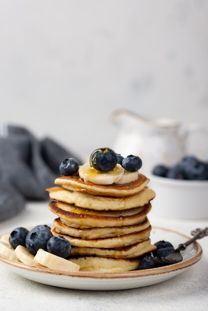 Vista frontale dei pancake della prima colazione con i mirtilli e le fette della banana