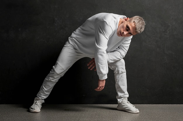 Vista frontale del ballerino maschio che posa in jeans e scarpe da tennis