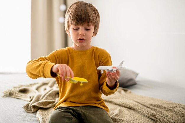 Vista frontale del bambino che gioca con le figurine dell'aeroplano