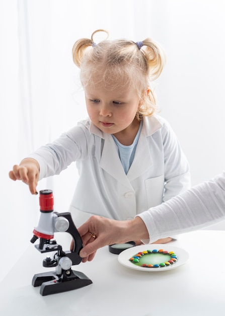 Vista frontale del bambino sveglio che impara sulla scienza con il microscopio