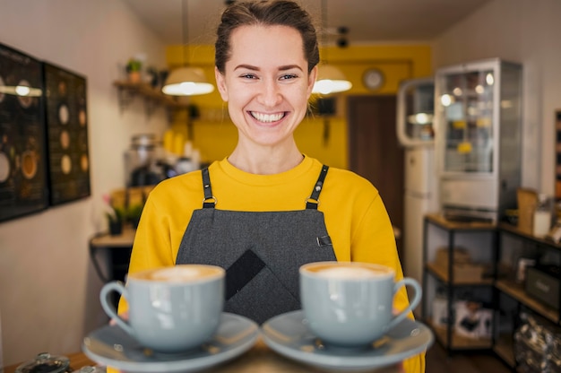 Vista frontale del barista di smiley che serve tazze di caffè