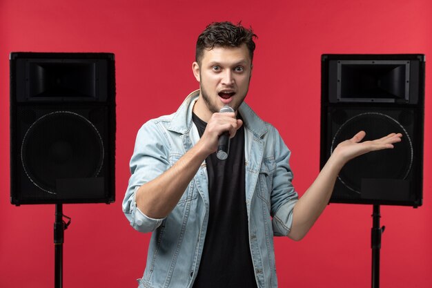 Vista frontale del cantante maschio che si esibisce sul palco sul muro rosso