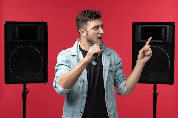 Vista frontale del cantante maschio che si esibisce sul palco sul muro rosso