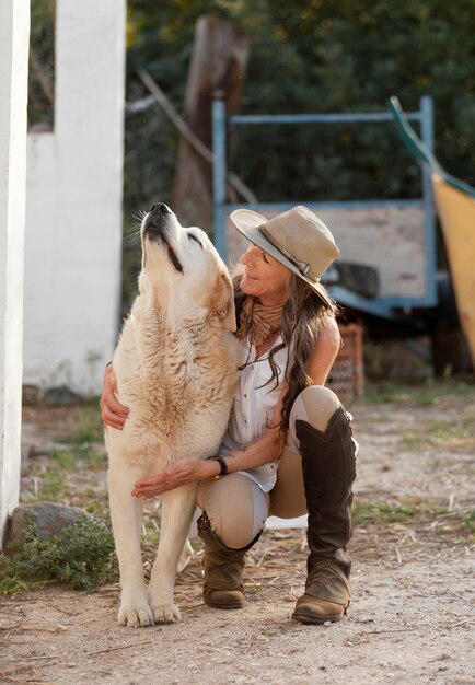 Vista frontale del coltivatore femminile che abbraccia il suo cane da fattoria