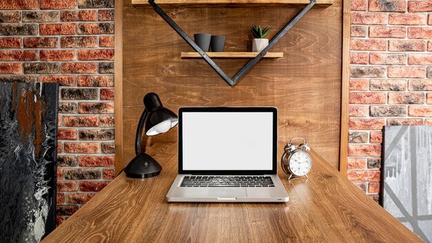 Vista frontale del computer portatile sull'area di lavoro dell'ufficio con lampada
