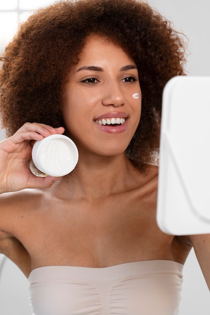 Vista frontale del contenitore della crema della holding della donna