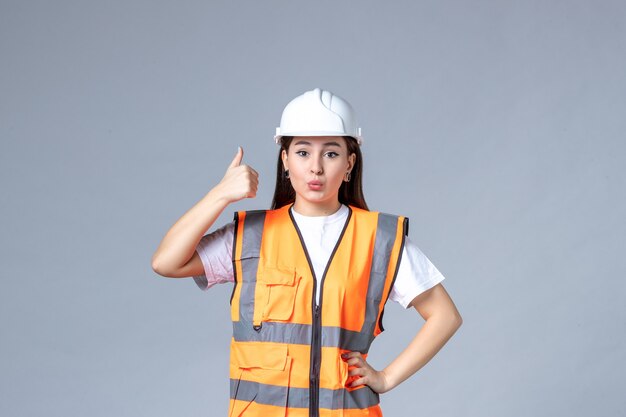 Vista frontale del costruttore femminile in uniforme sul muro bianco
