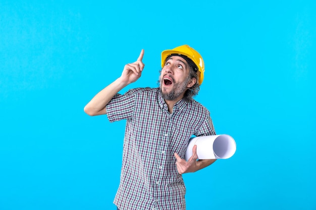 Vista frontale del costruttore maschio che tiene il piano su sfondo blu costruttore di architettura ingegnere lavoro edificio colore