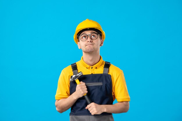 Vista frontale del costruttore maschio di pensiero in uniforme con il martello sull'azzurro