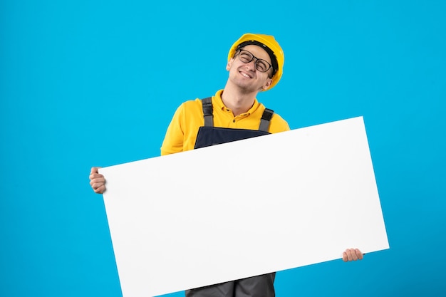 Vista frontale del costruttore maschio in uniforme gialla sull'azzurro