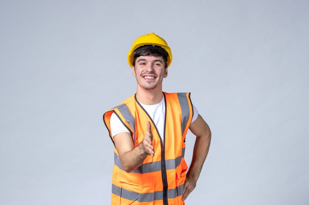 vista frontale del costruttore maschio in uniforme sul muro bianco