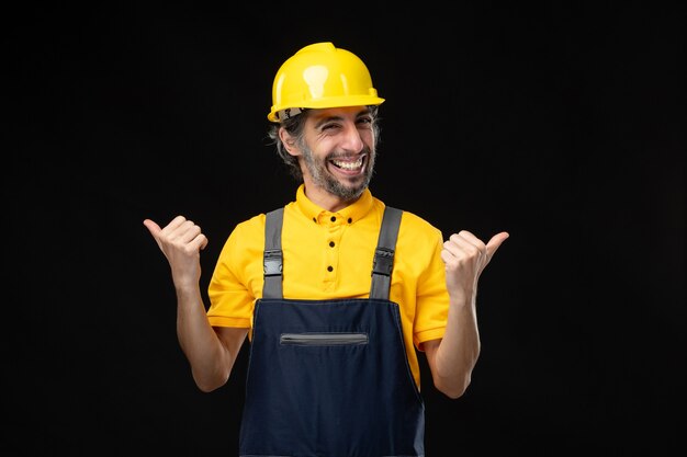 Vista frontale del costruttore maschio in uniforme sul muro nero