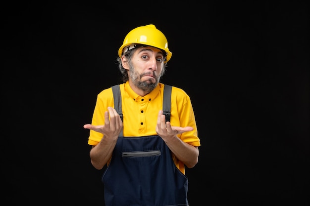 Vista frontale del costruttore maschio in uniforme sul muro nero