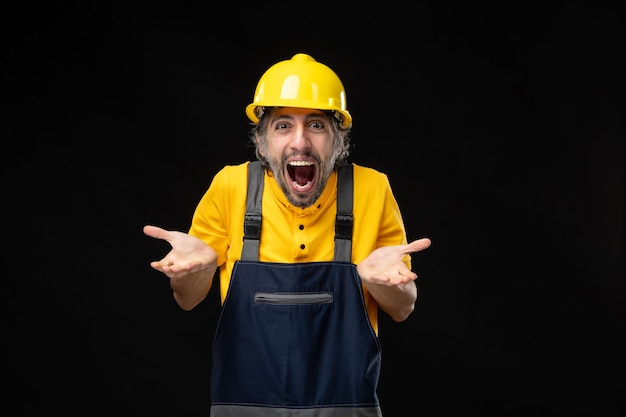 Vista frontale del costruttore maschio in uniforme sul muro nero