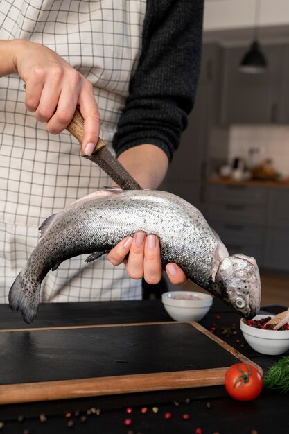Vista frontale del cuoco che pulisce il pesce in cucina