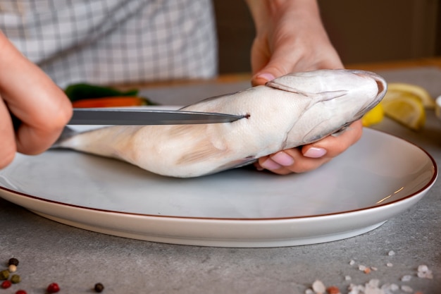 Vista frontale del cuoco che pulisce il pesce in cucina