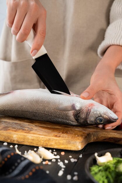 Vista frontale del cuoco che pulisce il pesce in cucina