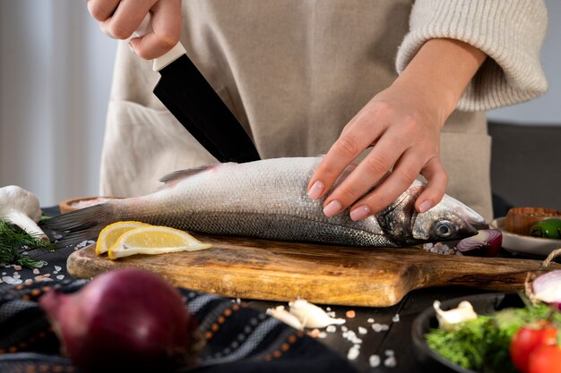 Vista frontale del cuoco che pulisce il pesce in cucina