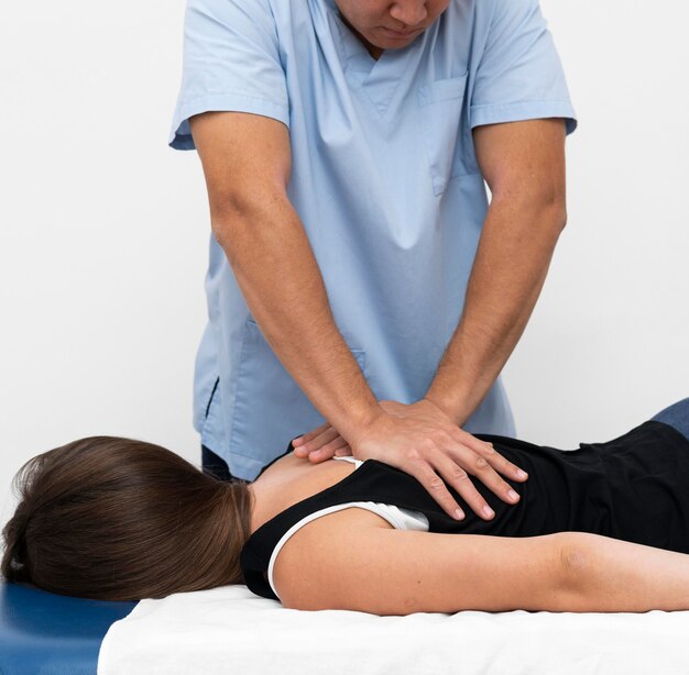 Vista frontale del fisioterapista che massaggia la schiena della donna