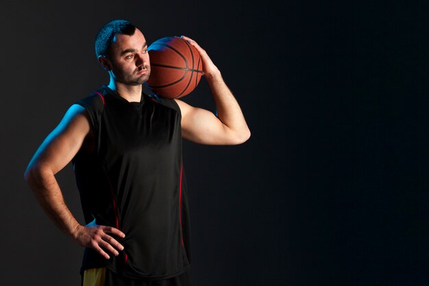 Vista frontale del giocatore di pallacanestro con la palla sulla spalla e lo spazio della copia