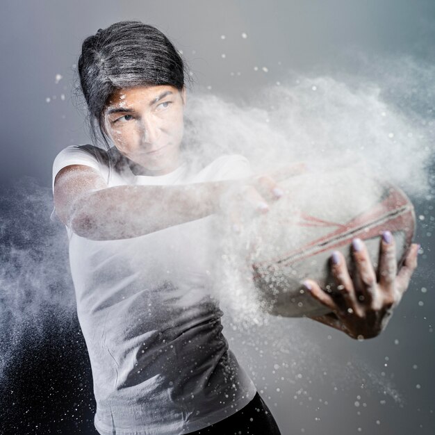 Vista frontale del giocatore di rugby femminile atletico che tiene palla con polvere