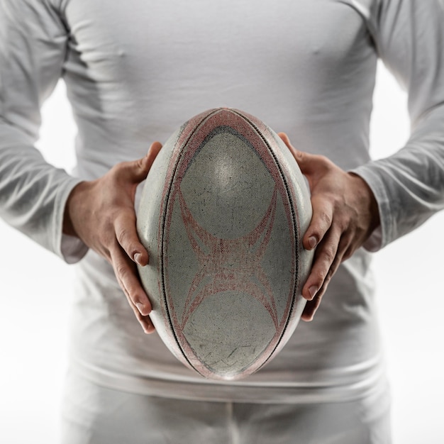 Vista frontale del giocatore di rugby maschio che tiene palla con entrambe le mani