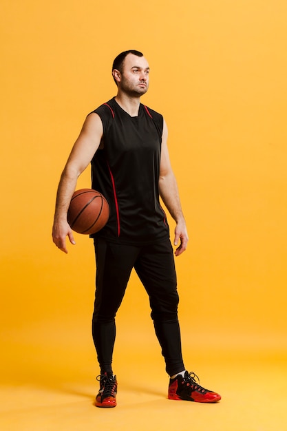 Vista frontale del giocatore maschio rilassato che posa con la pallacanestro