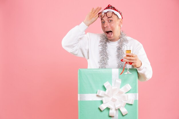 Vista frontale del giovane che celebra il Natale con un drink sulla parete rosa