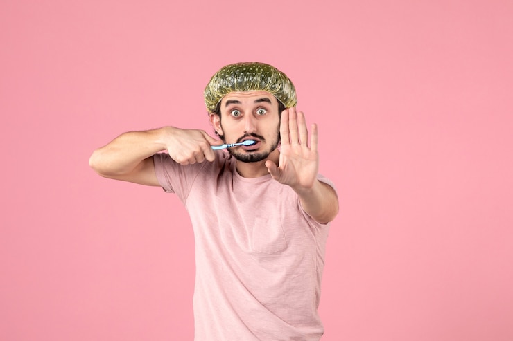 Foto gratuito vista frontale del giovane che si lava i denti sul muro rosa