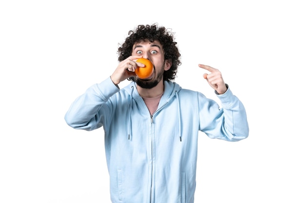 Vista frontale del giovane che tiene l'arancia fresca su sfondo bianco muscolo di salute che perde peso dimagrendo la misurazione del corpo umano della frutta