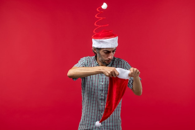 Vista frontale del giovane con cappuccio rosso di Natale sulla parete rossa