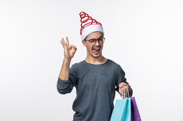 Vista frontale del giovane dopo lo shopping natalizio sul muro bianco