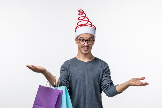 Vista frontale del giovane dopo lo shopping natalizio sul muro bianco