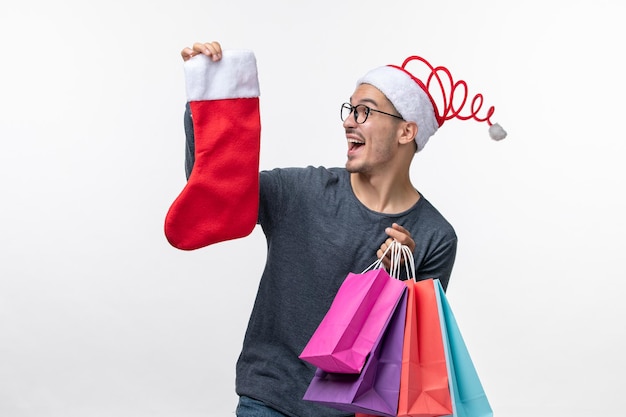 Vista frontale del giovane dopo lo shopping natalizio sul muro bianco