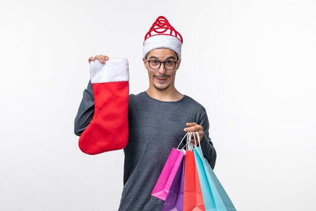 Vista frontale del giovane dopo lo shopping natalizio sul muro bianco