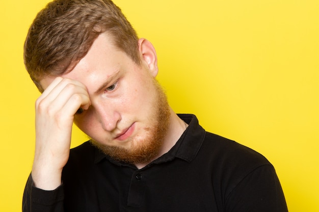 Vista frontale del giovane in camicia nera che posa con l'espressione depressa