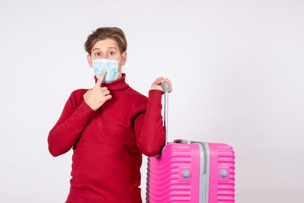 Vista frontale del giovane maschio che trasportano borsa rosa sul muro bianco